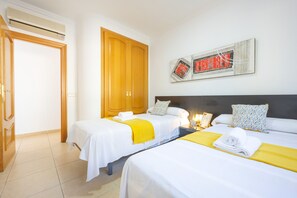 A hotel room with two beds, a wooden wardrobe, a wall-mounted artwork, and a bedside table with a lamp. - Villa Almendros - PlusHolidays (Calpe)