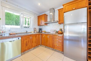 A modern kitchen with wooden cabinets, a stainless steel refrigerator, and a Bosch dishwasher.