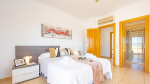 Una habitación de hotel con cama, mesita de noche, una obra de arte y la puerta del baño.