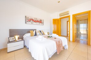 A hotel room with a bed, nightstand, artwork, and a bathroom door. - Villa Almendros - PlusHolidays (Calpe)