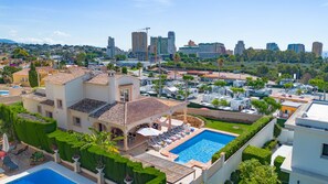 A large villa with a swimming pool, multiple guest rooms, and a view of the city skyline. - Villa Almendros - PlusHolidays (Calpe)