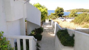 Un bâtiment blanc doté d’un escalier en colimaçon menant à un balcon qui offre une vue sur la côte.
