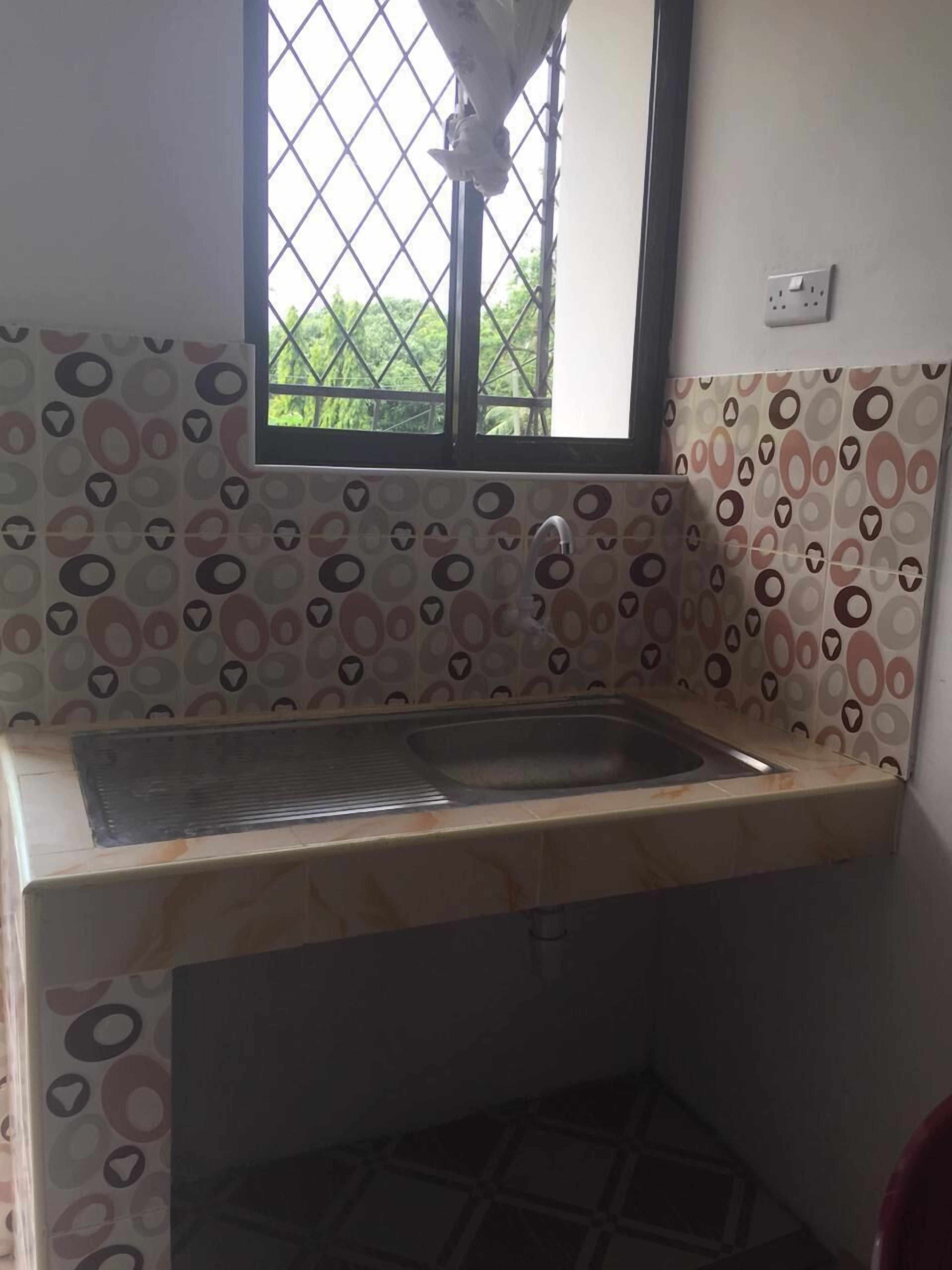 A kitchen with a window, patterned walls, and a sink.