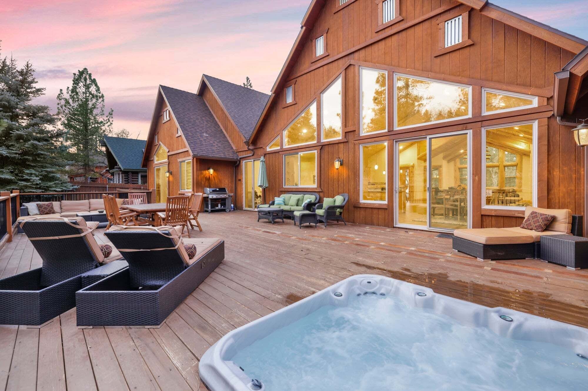 A wooden house with a hot tub, outdoor seating, and a deck.