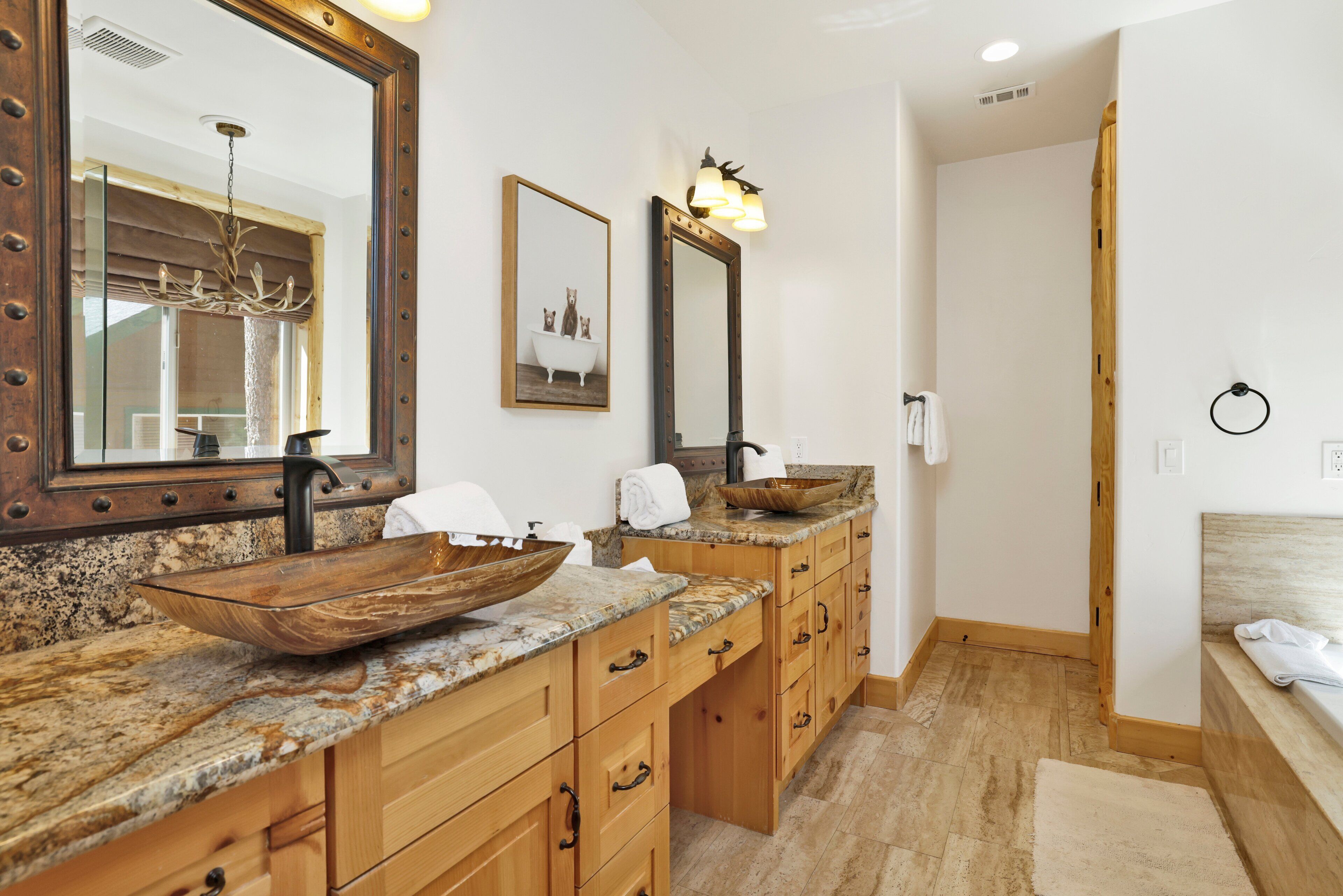 A bathroom with a wooden vanity, a large mirror, a vessel sink, and a shower area.