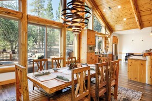 Un comedor espacioso con mobiliario de madera y grandes ventanales que ofrecen vistas al exterior.