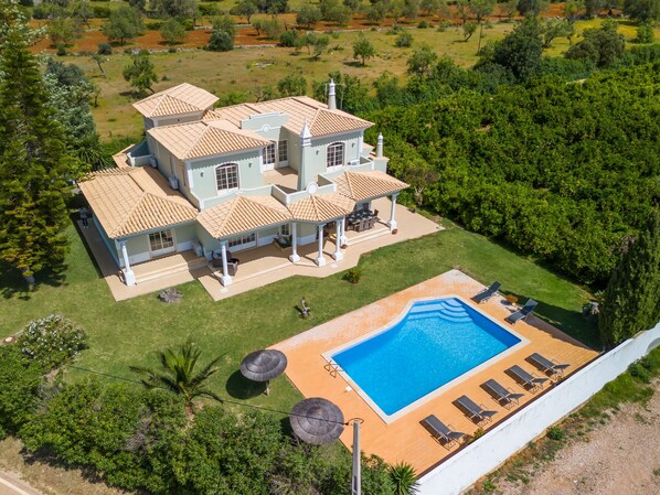 Ein großes Haus mit mehreren Zimmern, einem Swimmingpool und einem Garten.