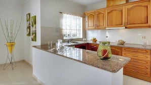 A kitchen with a granite countertop, wooden cabinets, and a window with curtains. - Villa Licinia - Three Bedroom Villa, Sleeps 6 (Guia)