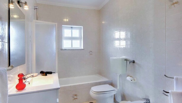 Ein Badezimmer mit Waschbecken, Toilette, Badewanne und Spiegel.