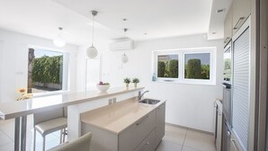 A modern kitchen with a central island, a built-in sink, and a window with a view of greenery. - Imagine Your Family Renting a Luxury Holiday Villa Close to Sotira’ Main Attractions (Sotira)