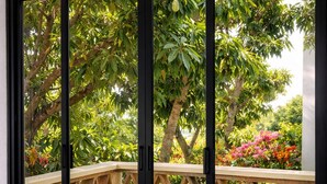 Une pièce dotée d’une porte-fenêtre coulissante qui donne sur un espace extérieur aménagé avec un banc en bois et de la verdure.