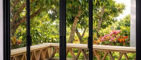 A room with a sliding glass door leading to an outdoor area with a wooden bench and greenery.