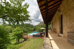 A pool area with lounge chairs and a wooden deck, surrounded by greenery and a stone building. - The Miller’s Cottage, cosy retreat, sleep 5, private pool, free Wifi (Nouvelle-Aquitaine)