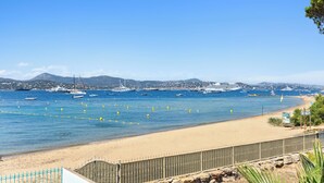 A coastal view with a sandy beach, a stone wall, and a metal fence. - VILLA - LES PIEDS DANS L'EAU - LA BOUILLABAISSE BEACH - ST TROPEZ - 14 PEOPLE (Saint-Tropez)