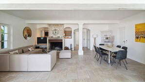 A spacious living area with a large sofa, a fireplace, and a dining table with chairs. - VILLA - LES PIEDS DANS L'EAU - LA BOUILLABAISSE BEACH - ST TROPEZ - 14 PEOPLE (Saint-Tropez)