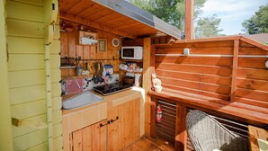 A compact wooden cabin with a kitchenette, including a sink, stove, and microwave.