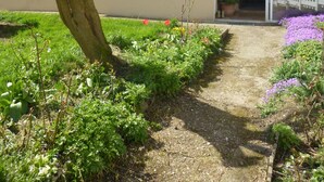 Een gebouw met twee verdiepingen en een tuin ervoor.