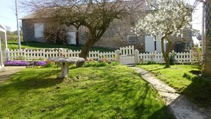 Een stenen gebouw met een witte picket hek, een tuin vol bloemen en een bankje.