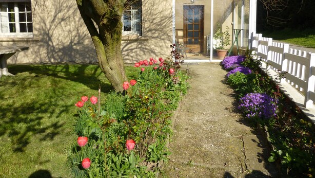 Een huis met een tuin, een witte hek en een deur die uitkomt op een overdekte veranda.