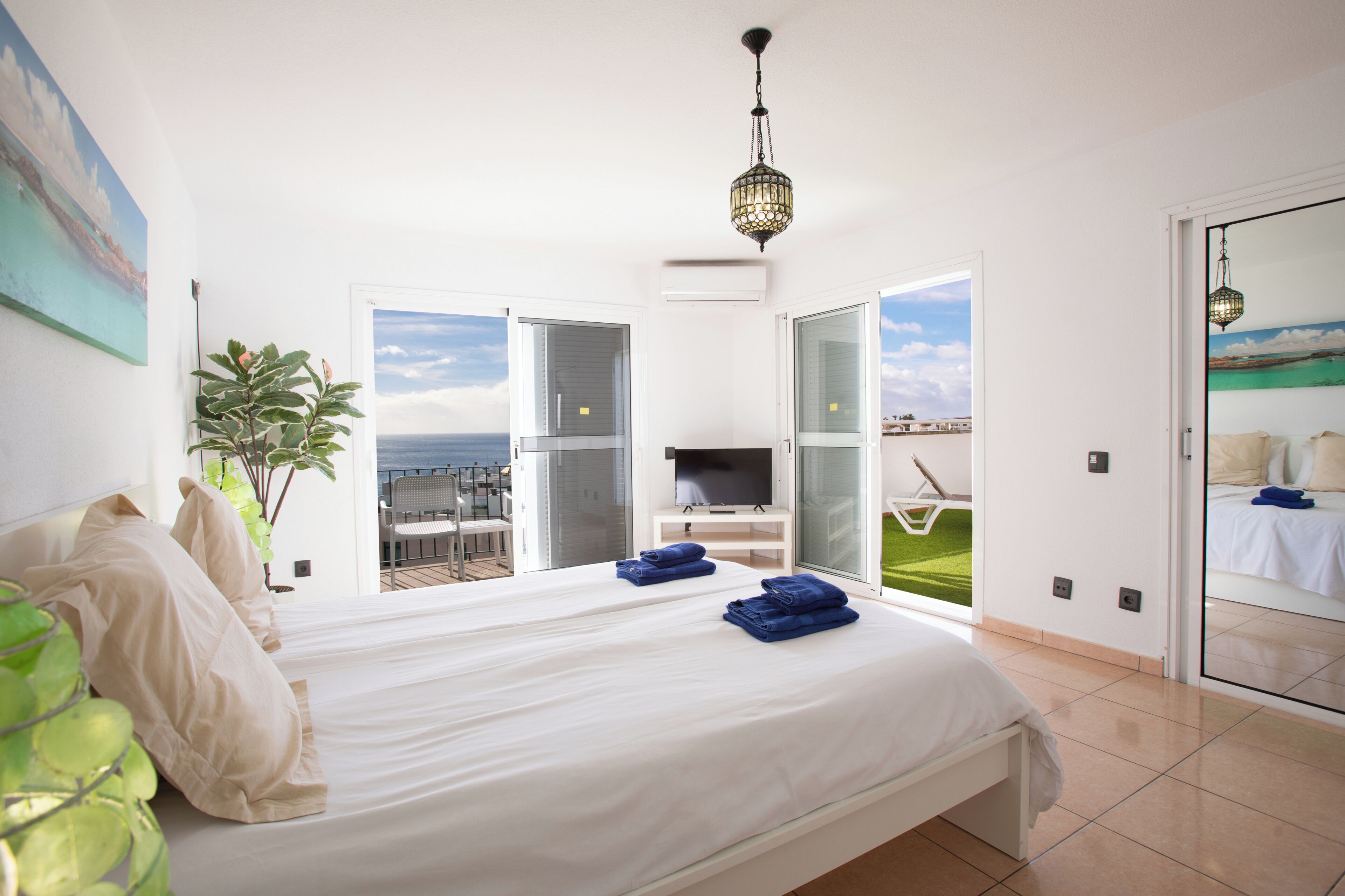 A bedroom with a bed, a TV, and a view of the sea.