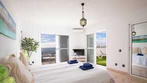 Quarto com cama, televisão e vista para o mar.