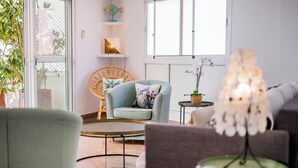 Uma sala de estar com um sofá, uma poltrona, uma mesa de centro e um vaso de planta.
