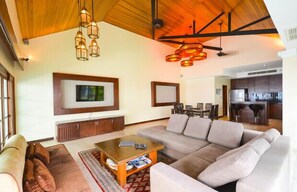 A spacious living room with a large sofa, a coffee table, and a television mounted on the wall.