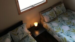 A small, cozy room with two beds, a window, and a nightstand with a lamp. - 10 Minutes From Waterton Park Boundary Lakeside Gallery & Guest House (Mountain View)