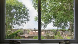 A window view of a garden with a stone wall, wooden chairs, and a grassy lawn. - 5 bedroom accommodation in Shap, near Penrith (Shap, near Penrith)