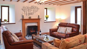 A cozy living room with a fireplace, leather sofas, and a coffee table. - 4 bedroom accommodation in Soar, near Brecon (Soar, near Brecon)