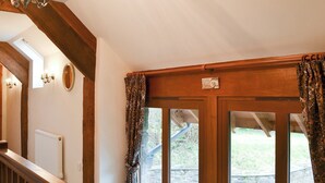A wooden staircase with a handrail, a white radiator, and a window with patterned curtains. - 4 bedroom accommodation in Soar, near Brecon (Soar, near Brecon)