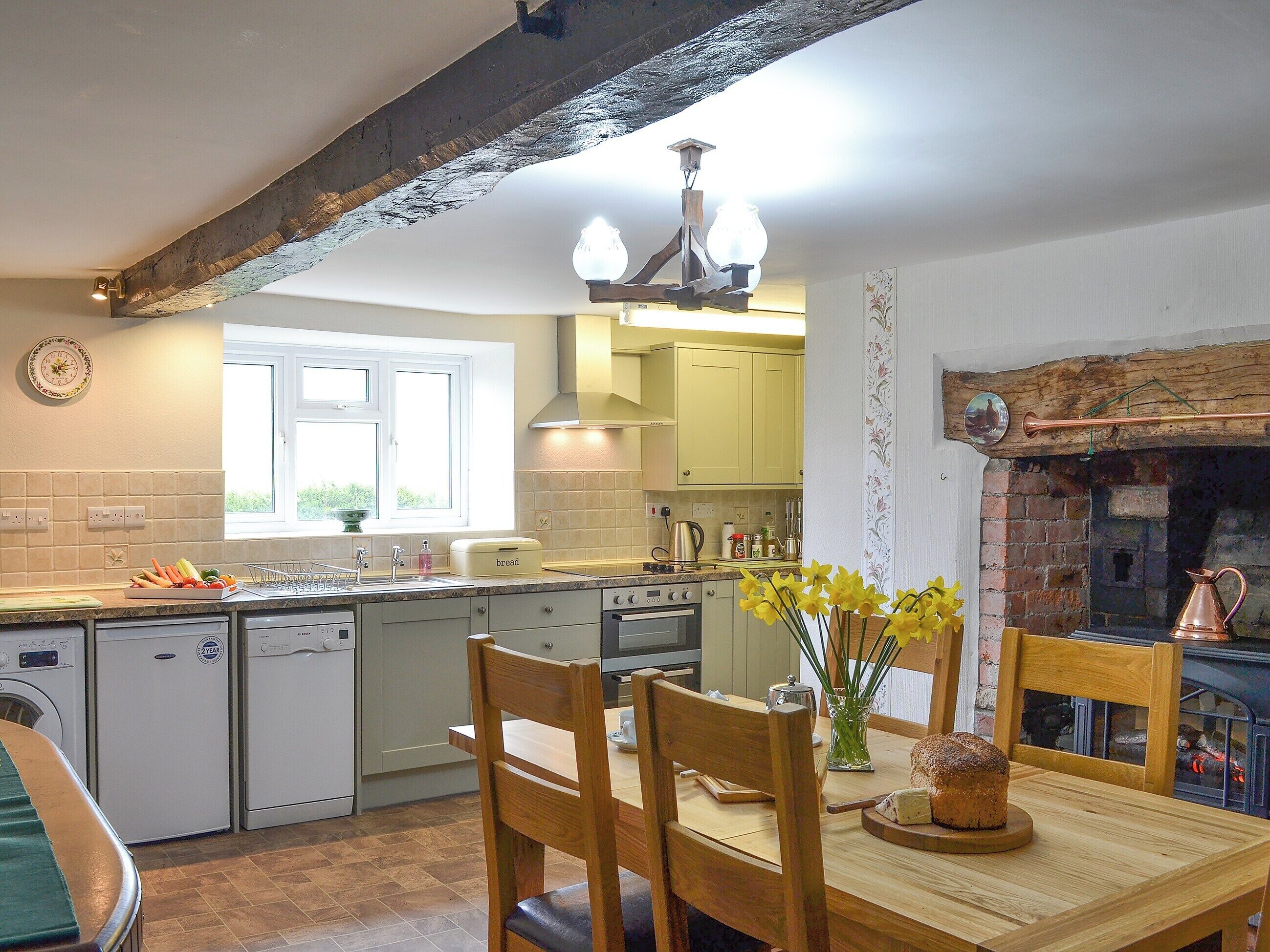 A kitchen with a dining table, chairs, a chandelier, and a fireplace.