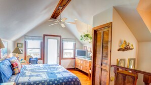A bedroom with a bed, a dresser, a television, and a ceiling fan.