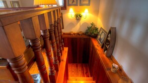 A wooden staircase with a handrail, a wall-mounted lamp, and a small shelf with decorative items.