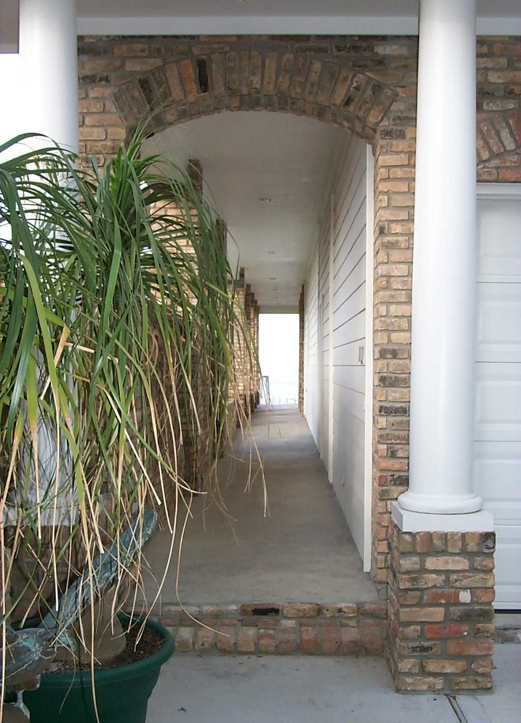 Une allée couverte, surmontée d’une arche en briques, mène à la porte du garage.