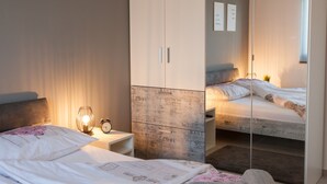A bedroom with a bed, bedside table, lamp, and a mirror.