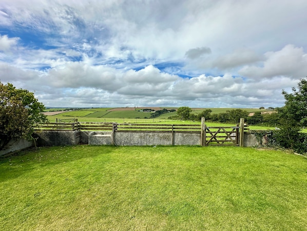 A rural landscape with a stone wall and wooden gate leading to a grassy field. - Two bedroom holiday cottage in a quiet rural location. (Lansallos)