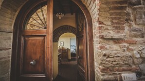 Un portale ad arco conduce a una stanza con un letto e una cassettiera. Un cartello appeso al muro indica "1 camera".