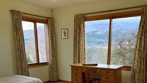 Une chambre avec deux lits, un bureau et de grandes fenêtres avec des rideaux.