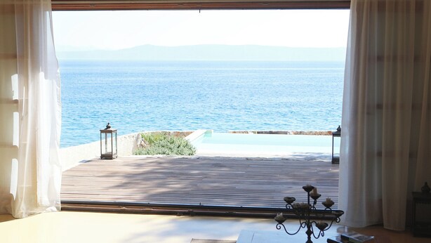 A room with a view of the sea, a wooden deck, and a chandelier. - Amazing seafront setting-Infinity pool (Sumartin)