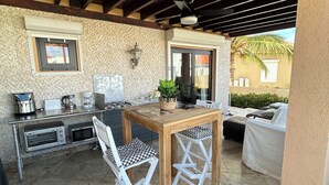 Un patio al aire libre con una mesa y sillas de madera, una parrilla y vistas al exterior.