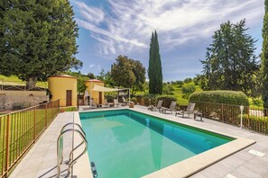 A rectangular swimming pool with a metal ladder, surrounded by a tiled deck, a fence, and various trees and shrubs. - Luxury Tuscan Hideaway with Heated Swimming Pool (Chiusi)