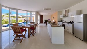 Una cucina moderna con isola centrale, ampie finestre e vista su una piscina.
