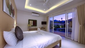 Una moderna camera d'hotel con un letto grande, una ventola a soffitto, un condizionatore d'aria, una TV e un balcone con vista sul paesaggio.
