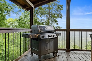 A portable grill on a wooden deck with a view of a forested landscape. - Mountain Crest Cabin-Relaxing Vacation in Jasper (Jasper)