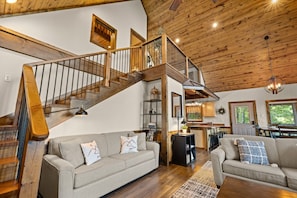 A spacious living room with a wooden staircase, two sofas, a dining area, and a kitchen. - Mountain Crest Cabin-Relaxing Vacation in Jasper (Jasper)