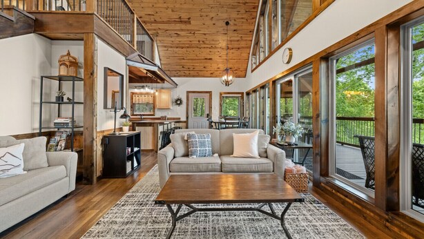 Un vaste espace de vie doté d’un plafond en bois, d’une grande fenêtre et d’un coin salon confortable.