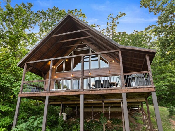 A wooden cabin with a balcony, large windows, and outdoor lighting. - Mountain Crest Cabin-Relaxing Vacation in Jasper (Jasper)
