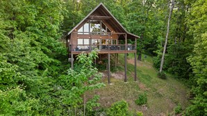 Une cabane dotée d’un balcon, entourée d’une forêt dense.