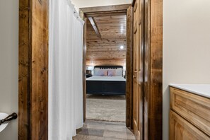 A narrow hallway leading to a bedroom with a wooden ceiling and a bed with pillows. - Mountain Crest Cabin-Relaxing Vacation in Jasper (Jasper)